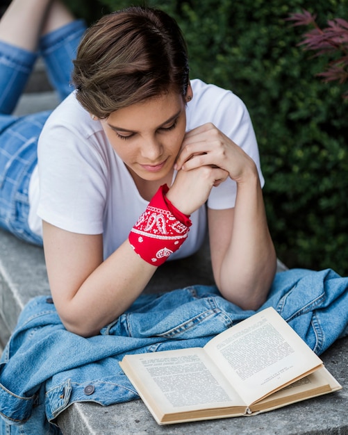 Foto gratuita libro de lectura femenina del estudiante que miente en el parapeto