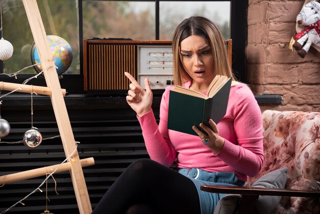 Libro de lectura hermosa joven intensamente en casa.