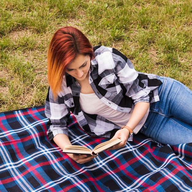 Foto gratuita libro de lectura hermoso de la mujer joven en el parque