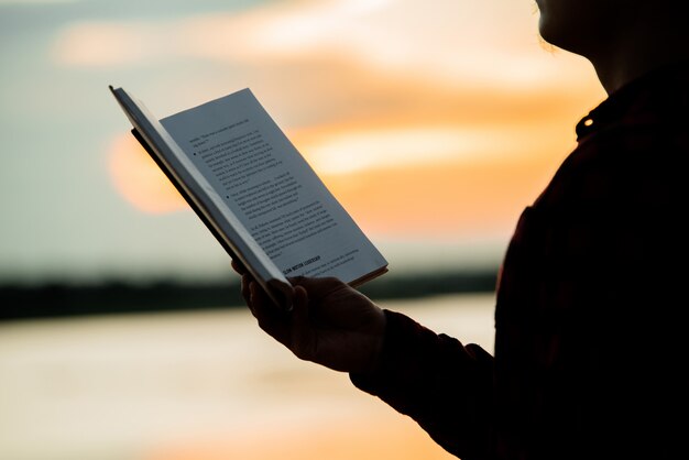 Libro de lectura del hombre asiático durante una puesta de sol