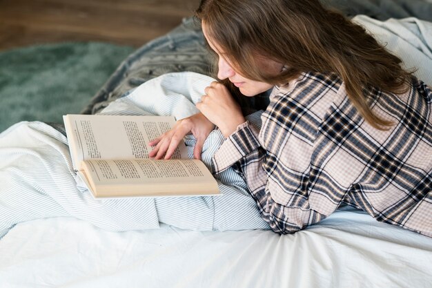 Libro de lectura de mujer caucásica en la cama