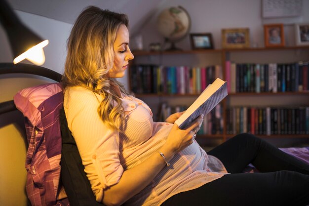Libro de lectura de mujer embarazada en la noche