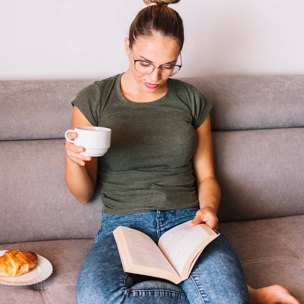 Foto gratuita libro de lectura de la mujer joven mientras que desayunando