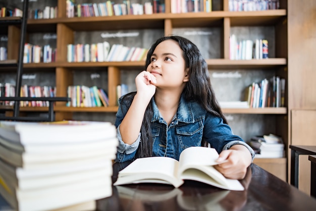 Libro de lectura de la mujer joven que se sienta interior en café urbano.