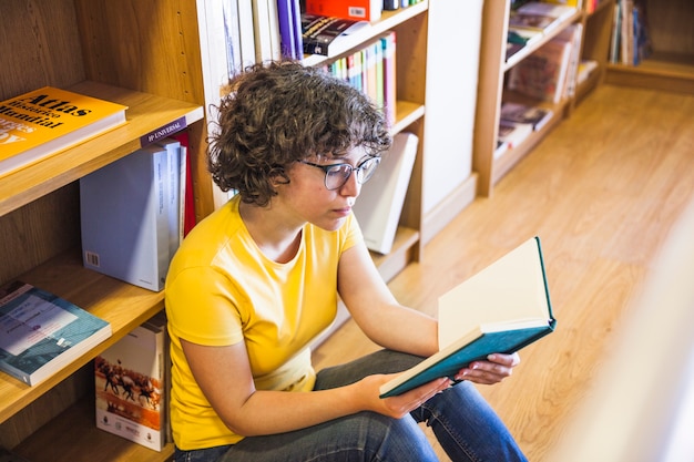 Libro de lectura de mujer sentado en el piso