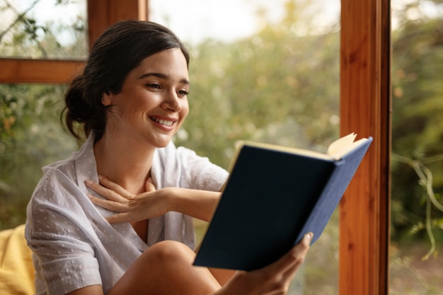 Foto gratuita libro de lectura de mujer sonriente de tiro medio