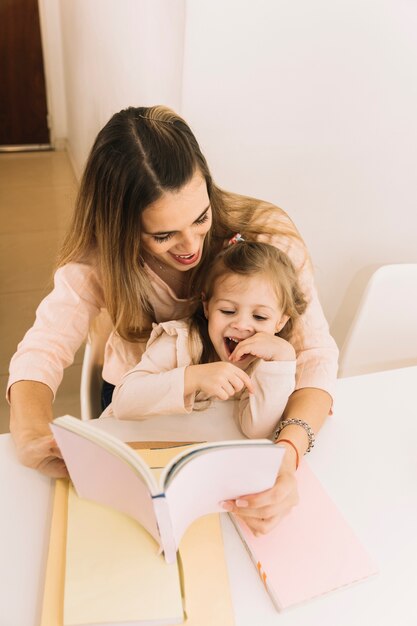 Libro de lectura de niña riendo con madre