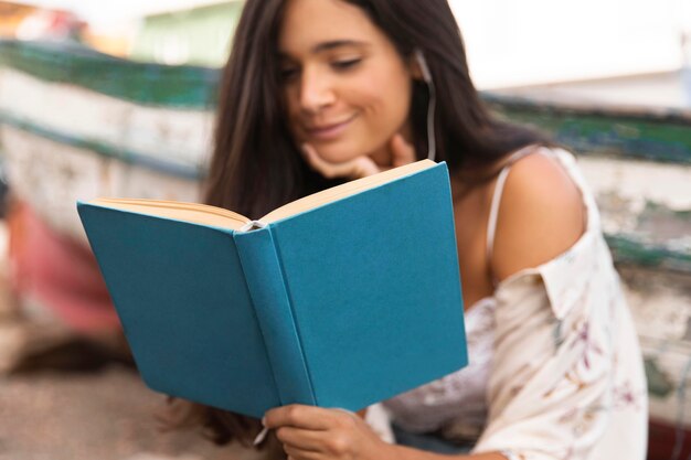 Libro de lectura de niña sonriente de tiro medio