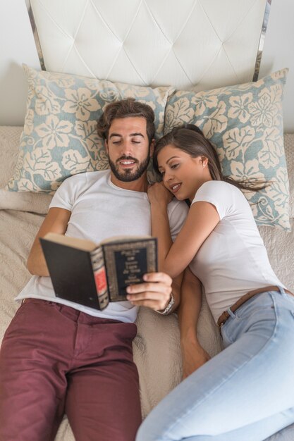 Libro de lectura de pareja en la cama juntos