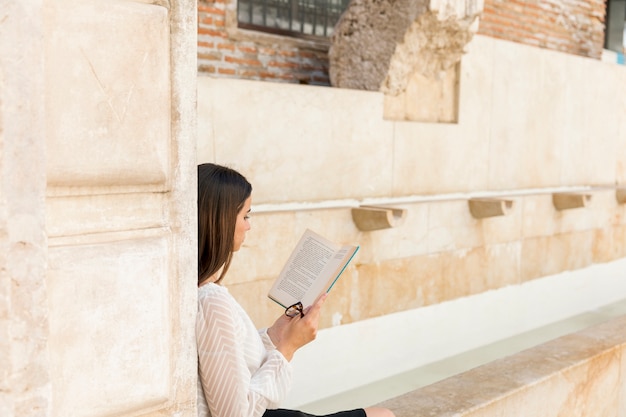 Libro de lectura de la señora joven y sostener los vidrios