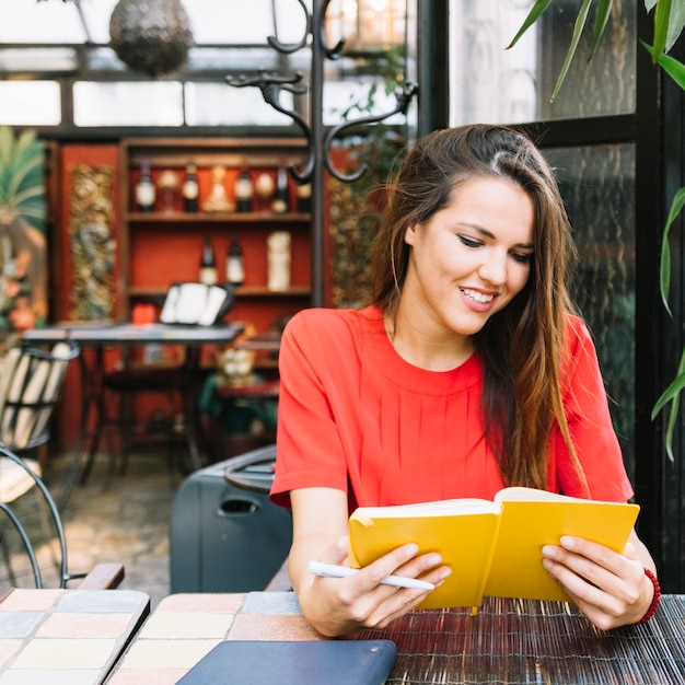 Libro de lectura sonriente de la mujer joven