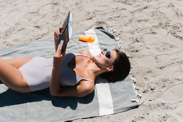 Libro de lectura sonriente de la mujer en la playa