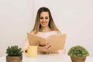 Foto gratuita libro de lectura sonriente de la mujer en la tabla