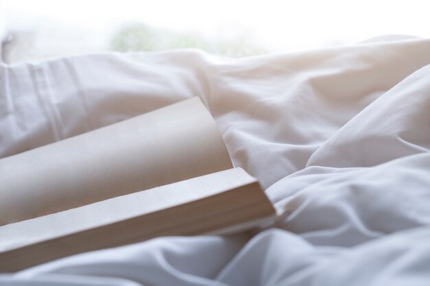 Libro de la página vacía en la cama blanda en la mañana.