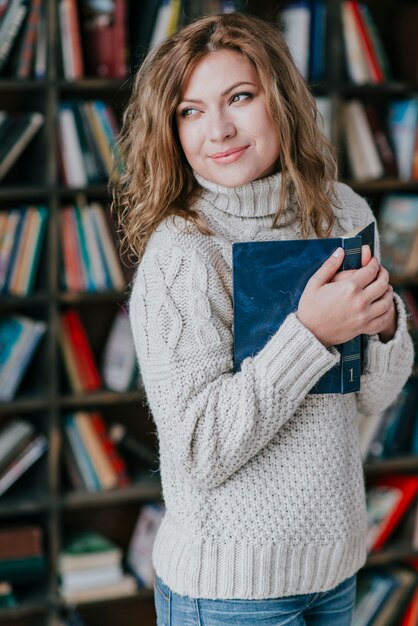 Libro que abraza sonriente de la mujer