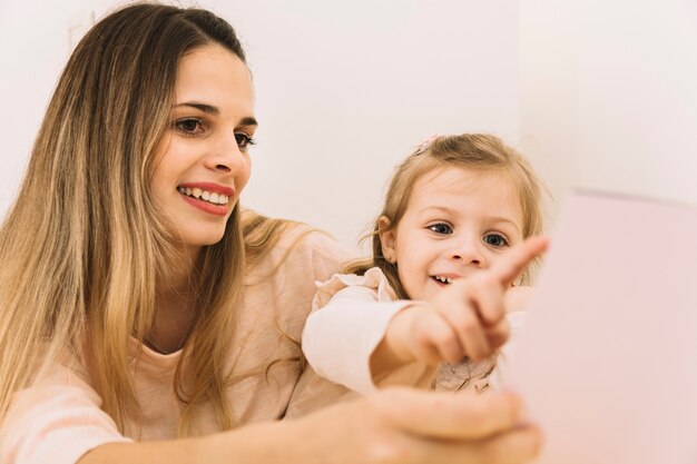 Libro señalador alegre de la muchacha mientras que lee con la madre