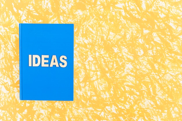 Libro de tapa azul Ideas sobre fondo amarillo