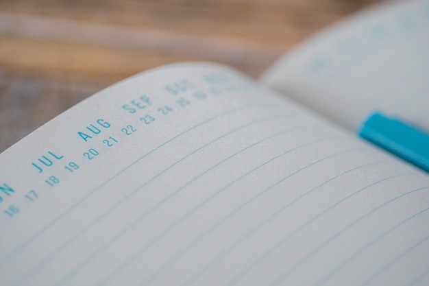 Foto gratuita libro de texto azul abierto con marcadores de fecha en la parte superior sobre una superficie de madera