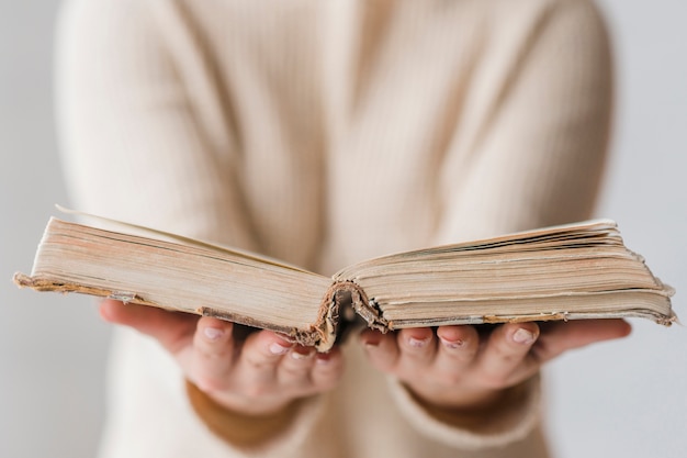 Un libro viejo abierto en la mano de la mujer.