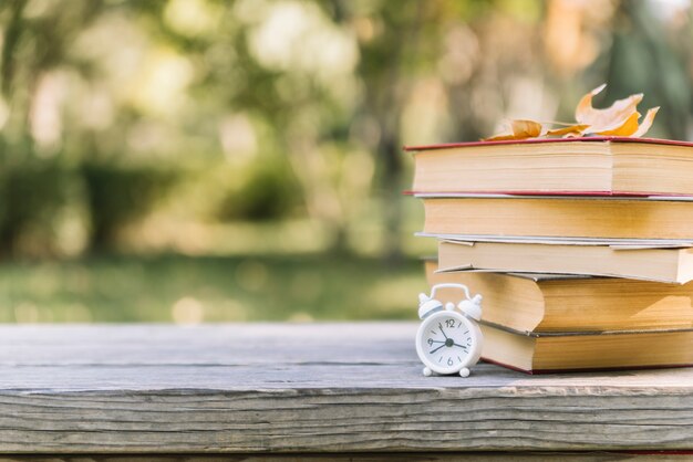 Libros apilados con reloj en una mesa