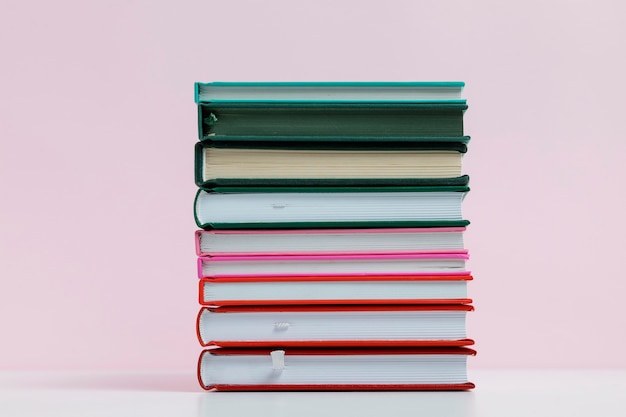 Libros coloridos con fondo rosa