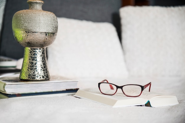 Libros con gafas y lámpara en la cama