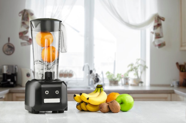 La licuadora eléctrica para hacer jugo de frutas o batidos en la mesa de la cocina de madera. El concepto de una dieta saludable.