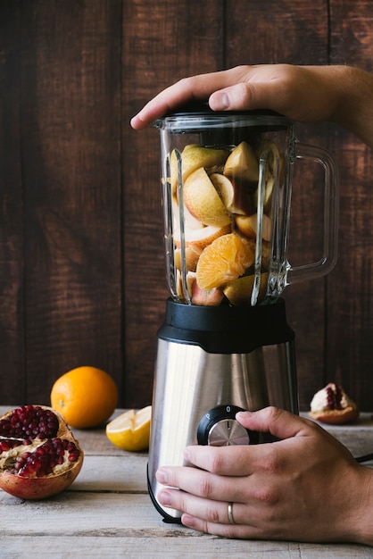 Licuadora con varias frutas sobre fondo de madera