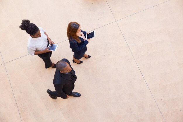 Líder empresarial y sus ayudantes femeninas caminando por la oficina.