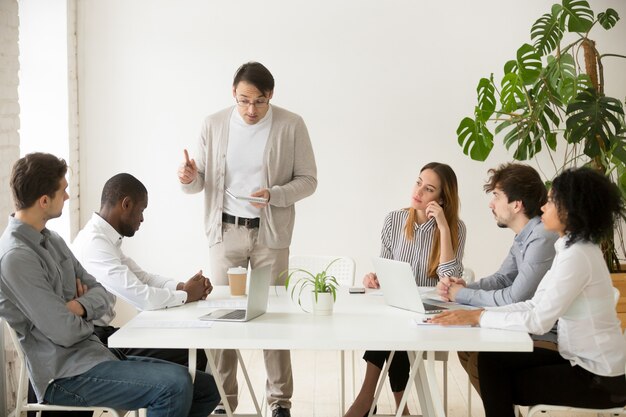 Líder del equipo caucásico reprendiendo al empleado africano por error en la reunión