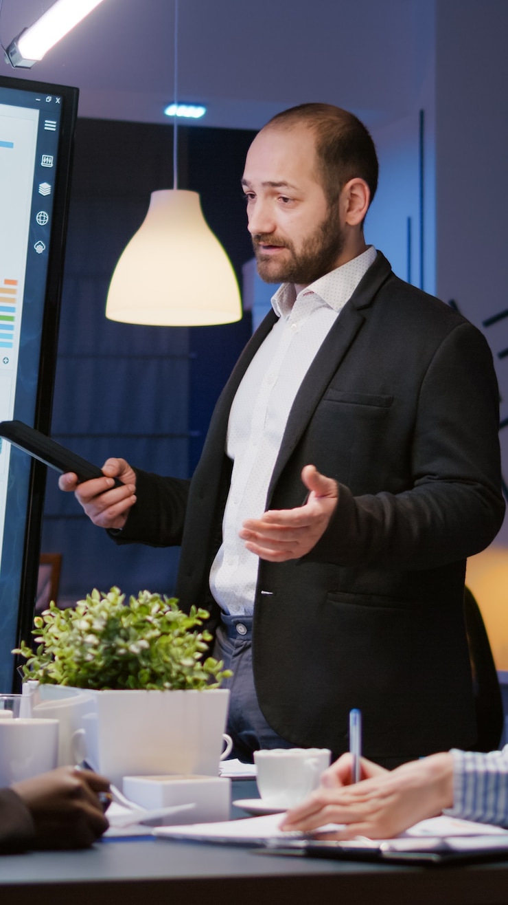 Foto gratuito líder de hombre enfocado explicando el proyecto de gestión usando el monitor trabajando en la sala de oficina de reuniones de la empresa ...