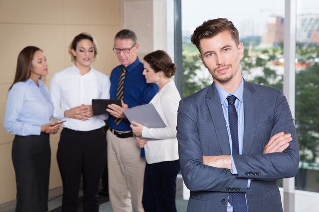 Líder de negocios confidente con el equipo en el fondo