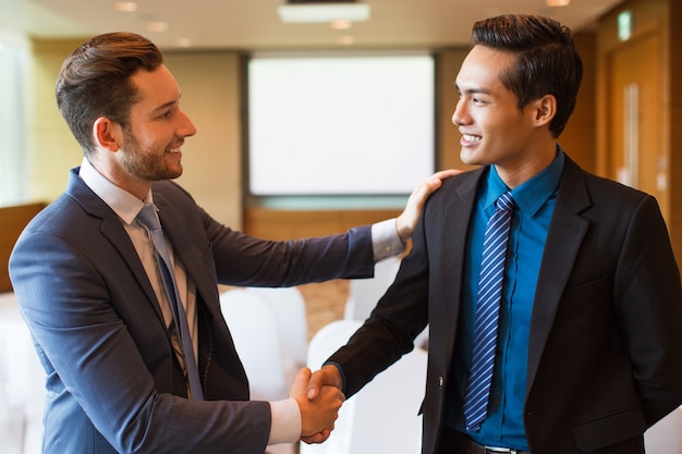 Líder de negocios sonriente felicitando colega