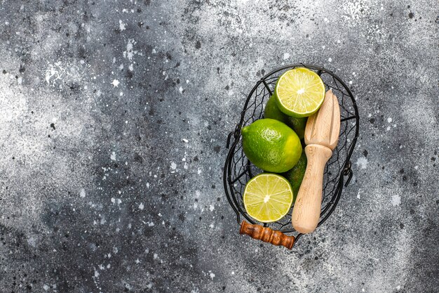 Limas frescas con exprimidor de cítricos de madera, vista superior