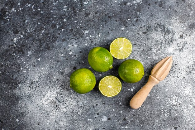 Limas frescas con exprimidor de cítricos de madera, vista superior