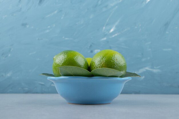 Limas maduras frescas en un tazón azul.