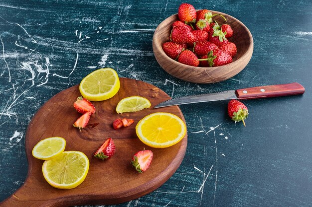 Limón y fresas en una tabla de madera.