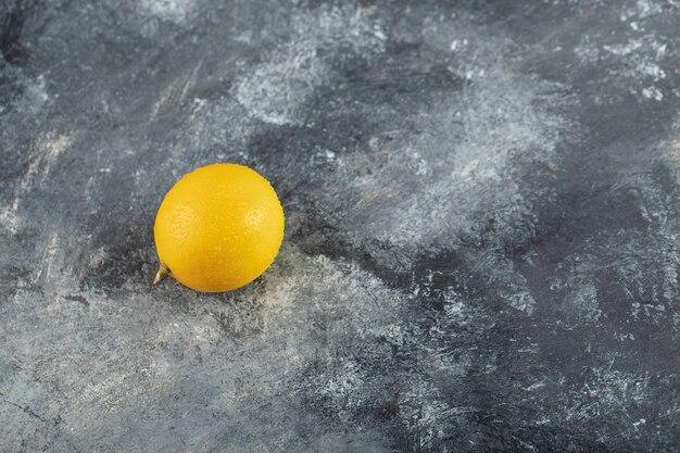 Un limón maduro amarillo sobre una superficie de mármol.