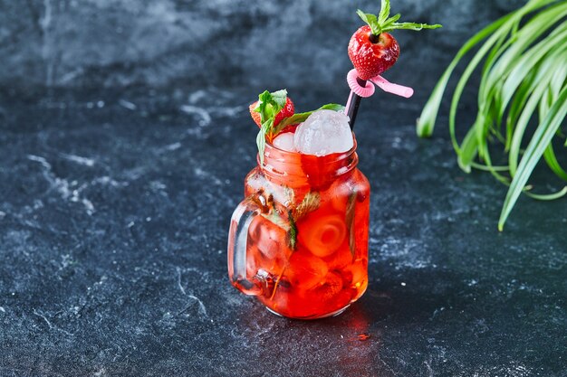 Limonada de fresa con hielo, menta paja en la superficie oscura