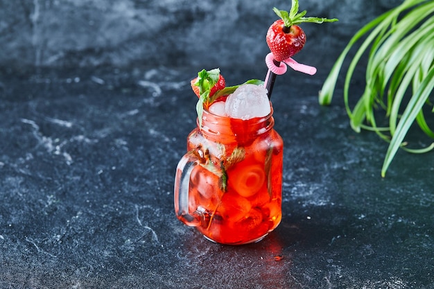 Limonada de fresa con hielo, menta paja en la superficie oscura