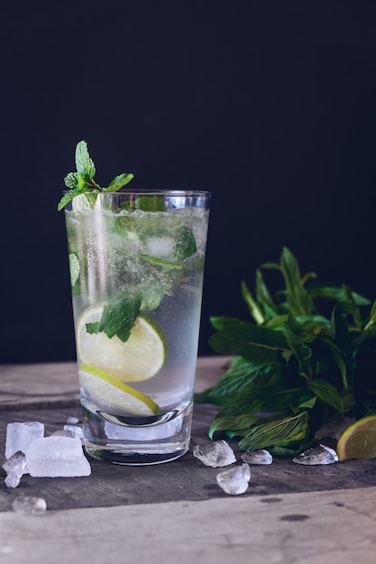 limonada de hielo con limón en un vaso de vidrio sobre un negro