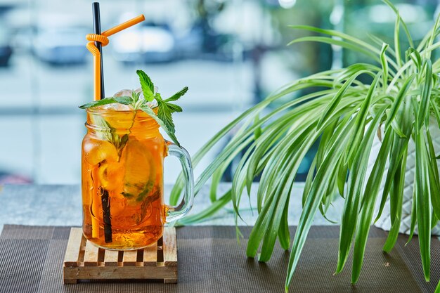 Limonada jugosa con paja y menta en la superficie de la planta