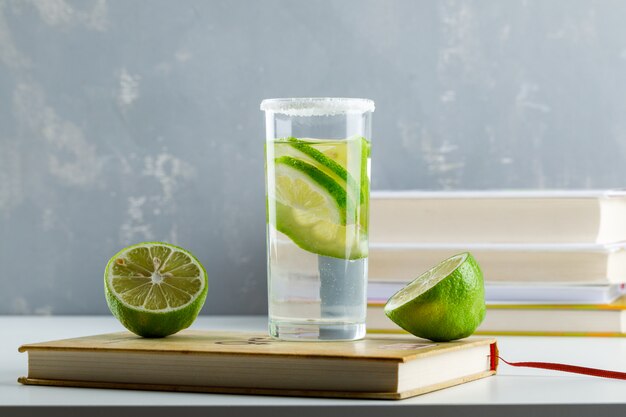 Limonada con limón, cuadernos, libros en un vaso en blanco y yeso,