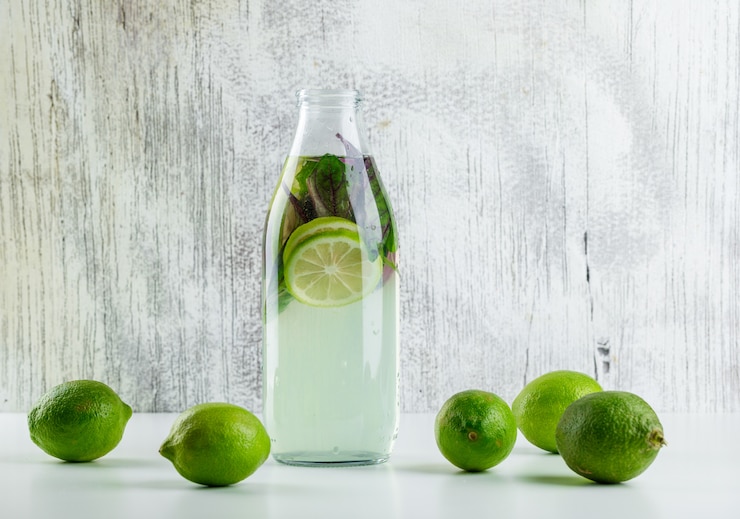 Foto gratuito limonada con limones, hojas de albahaca en una botella en blanco y sucio,