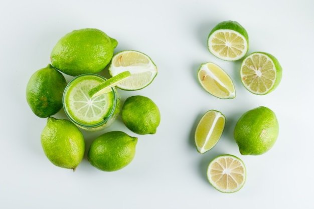 Limonada en un vaso con limones, hierbas, paja vista superior sobre un blanco