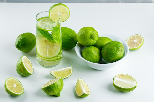 Limonada en un vaso con limones, hierbas vista de ángulo alto en blanco y gris