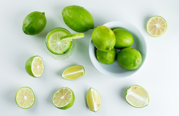 Limonada en un vaso con limones, paja plana sobre un blanco