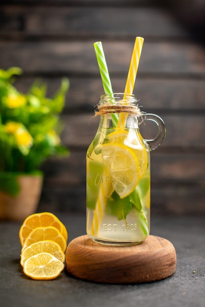 Limonada de vista frontal en tablero de madera para servir rodajas de limón planta en maceta sobre superficie marrón