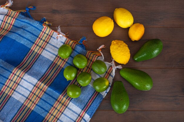 limones con aguacates sobre tela colorida sobre superficie de madera marrón cítricos