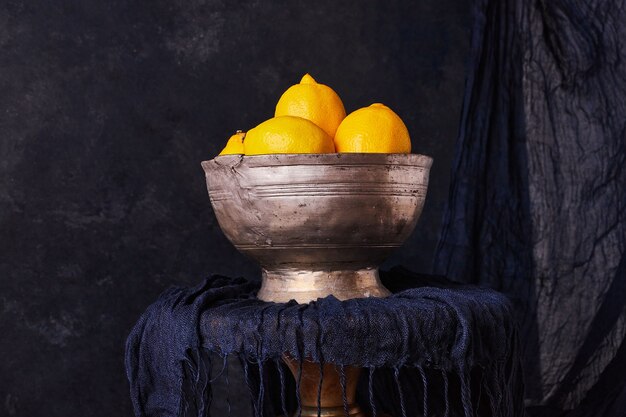 Limones amarillos en un cuenco étnico metálico.